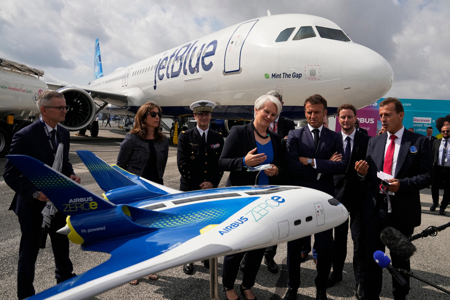 French President Emmanuel Macron, middle, and Airbus CEO Guillaume Faury, right, look at the concept hybrid-hydrogen aircraft Airbus Zero during the International Paris Air Show at the ParisLe Bourget Airport on June 19, 2023.
