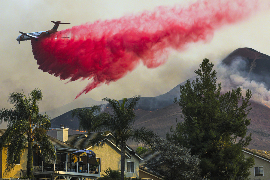 An air tanker makes a fire retardant drop behind homes on Oct. 27, 2020, in Chino Hills, California.