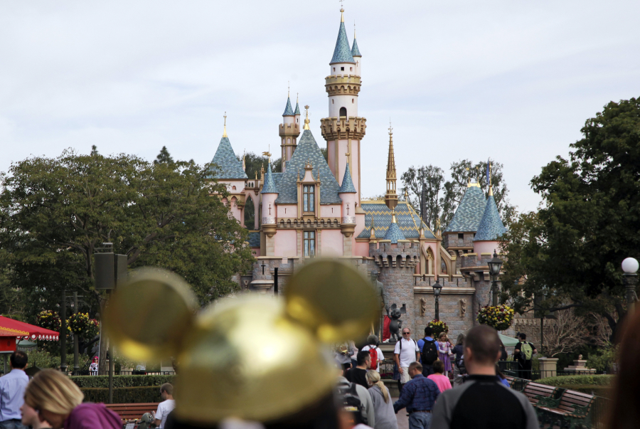 Visitors walk toward the Sleeping Beauty's Castle in the background at Disneyland Resort in Anaheim, Calif.