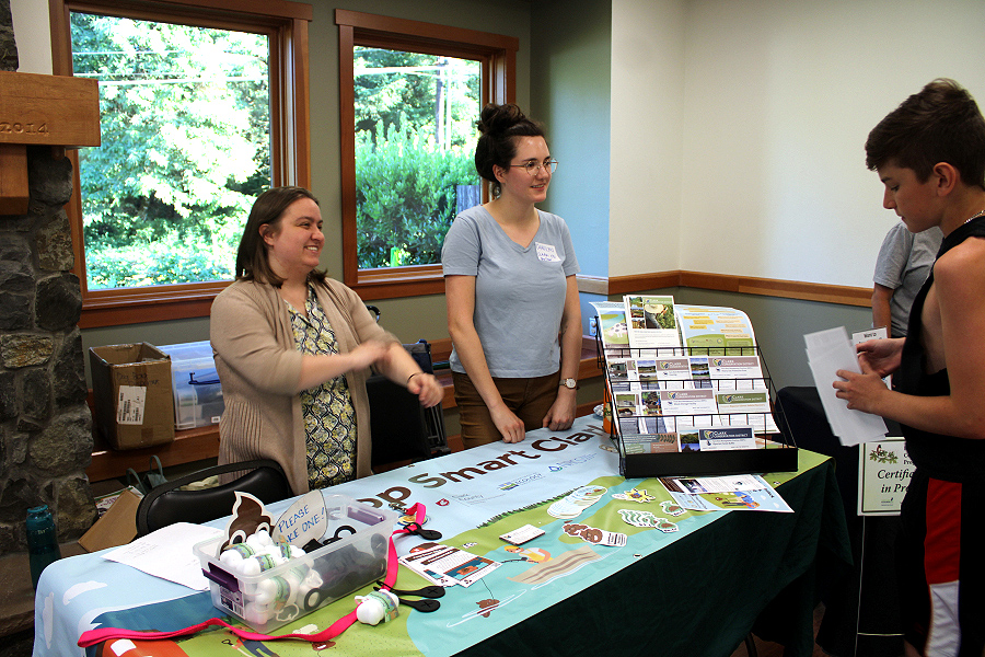Grace DeMeo, left, and Carolyn Rice, with Clark Conservation District, talk to members of the public about the District's Poop Smart program, which offers financial assistance for people hoping to replace or repair failing septic systems and educates the public on the benefits of keeping animal feces out of the watershed, during a lake water-quality open house held Wednesday, July 12, 2023, at Lacamas Lake Lodge in Camas.