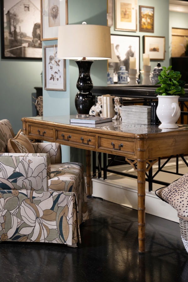 A desk steals the spotlight with its exquisite chippendale side panel, accentuated by acrylic pulls with brass accents.
