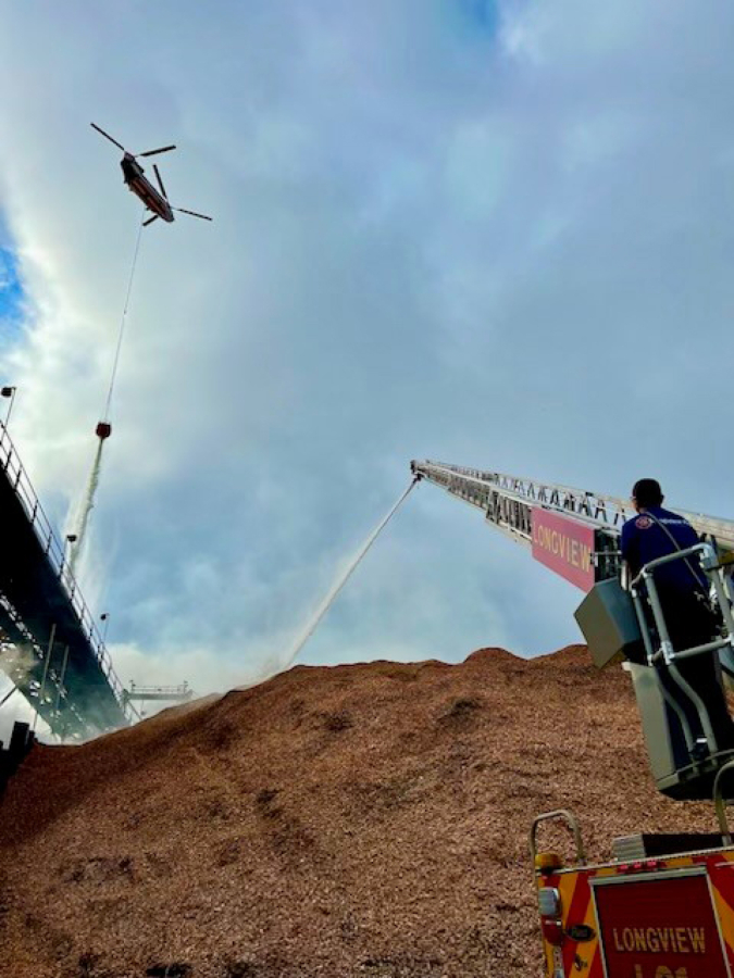 A Longview Fire Department crew, aided by a helicopter, attack a wood chip pile fire burning at a mill in Longview in this photo released on Thursday.