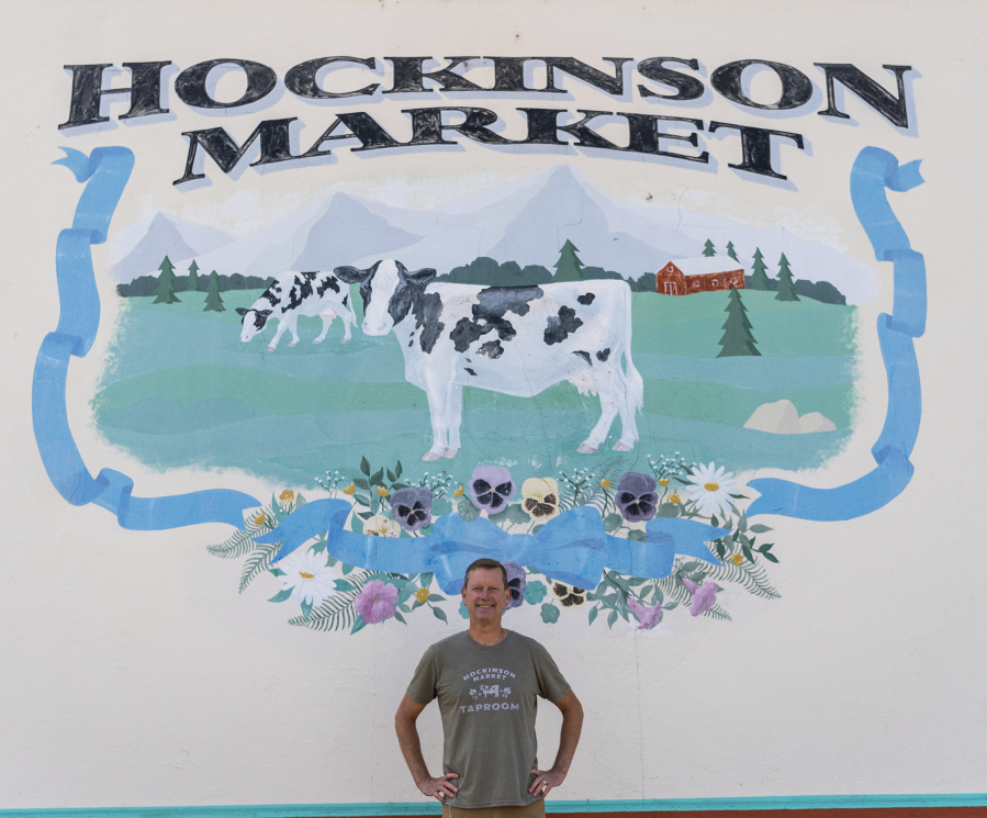 Hockinson Market owner Jim VanNatta stands in front of a mural on the store's north side. The cow is a nod to the building's 1928 origins with the Hockinson Dairy Co-Op Association.