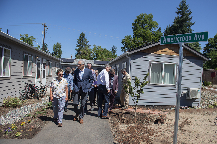 Gov. Jay Inslee, in blue blazer, talks with local officials and members of the community while getting a tour of Fruit Valley Terrace, an affordable housing complex of tiny homes.