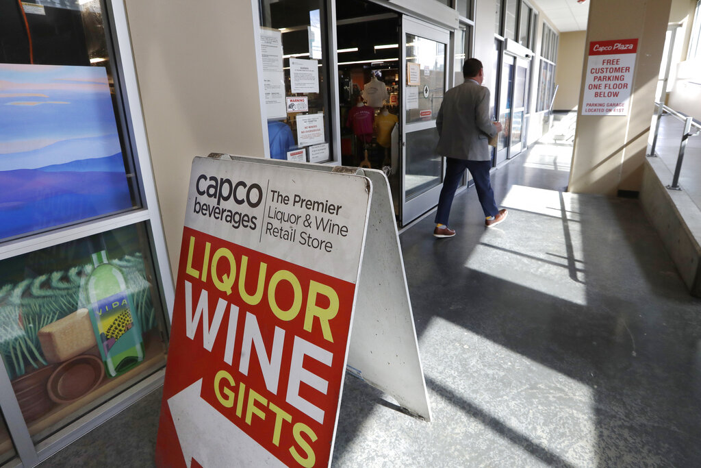 In this photo taken Wednesday, March 25, 2020, a shopper leaves a liquor store in Seattle.