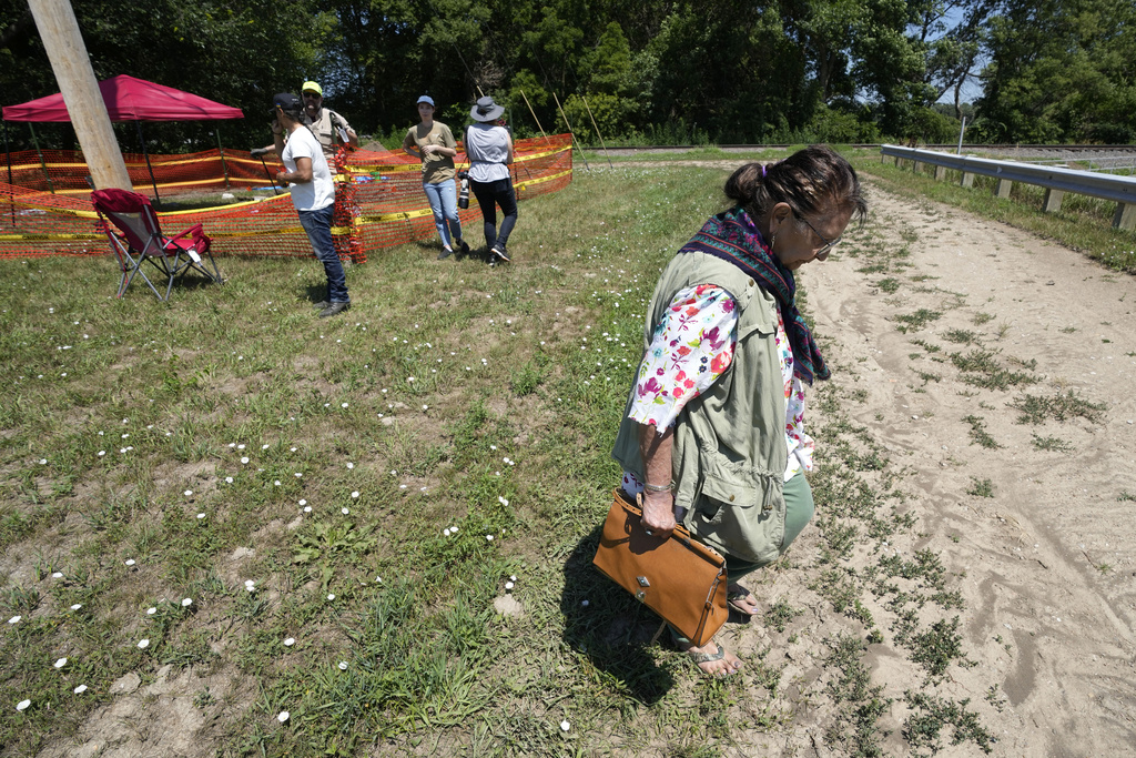 Loretta Jordan, of Omaha, Neb., walks near the site where workers are digging for the suspected remains of children who once attended the Genoa Indian Industrial School, Monday, July 10, 2023, in Genoa, Neb. The mystery of where the bodies of more than 80 children are buried could be solved this week as archeologists dig in a Nebraska field that a century ago was part of a sprawling Native American boarding school.