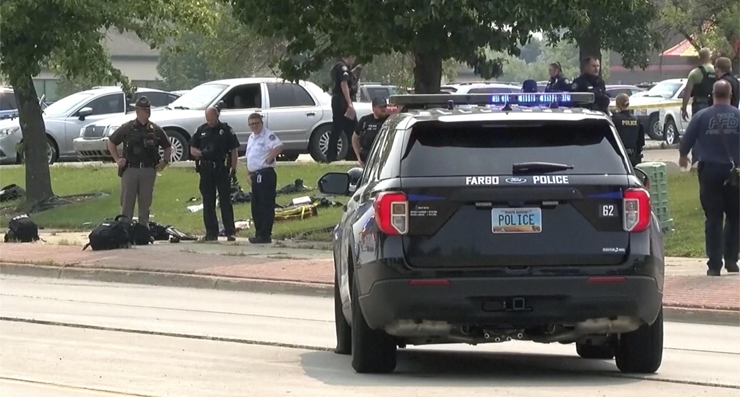 In this image from video, law enforcement officers work at the scene of a shooting Friday, July 14, 2023, in Fargo, N.D. One police officer died and two others were critically injured in the shooting that also killed the suspect, police said. The shooting happened before 3 p.m. on a busy street. Multiple witnesses said a man opened fire on police officers before other officers shot the suspect. In a statement late Friday, police said a civilian also was seriously wounded.
