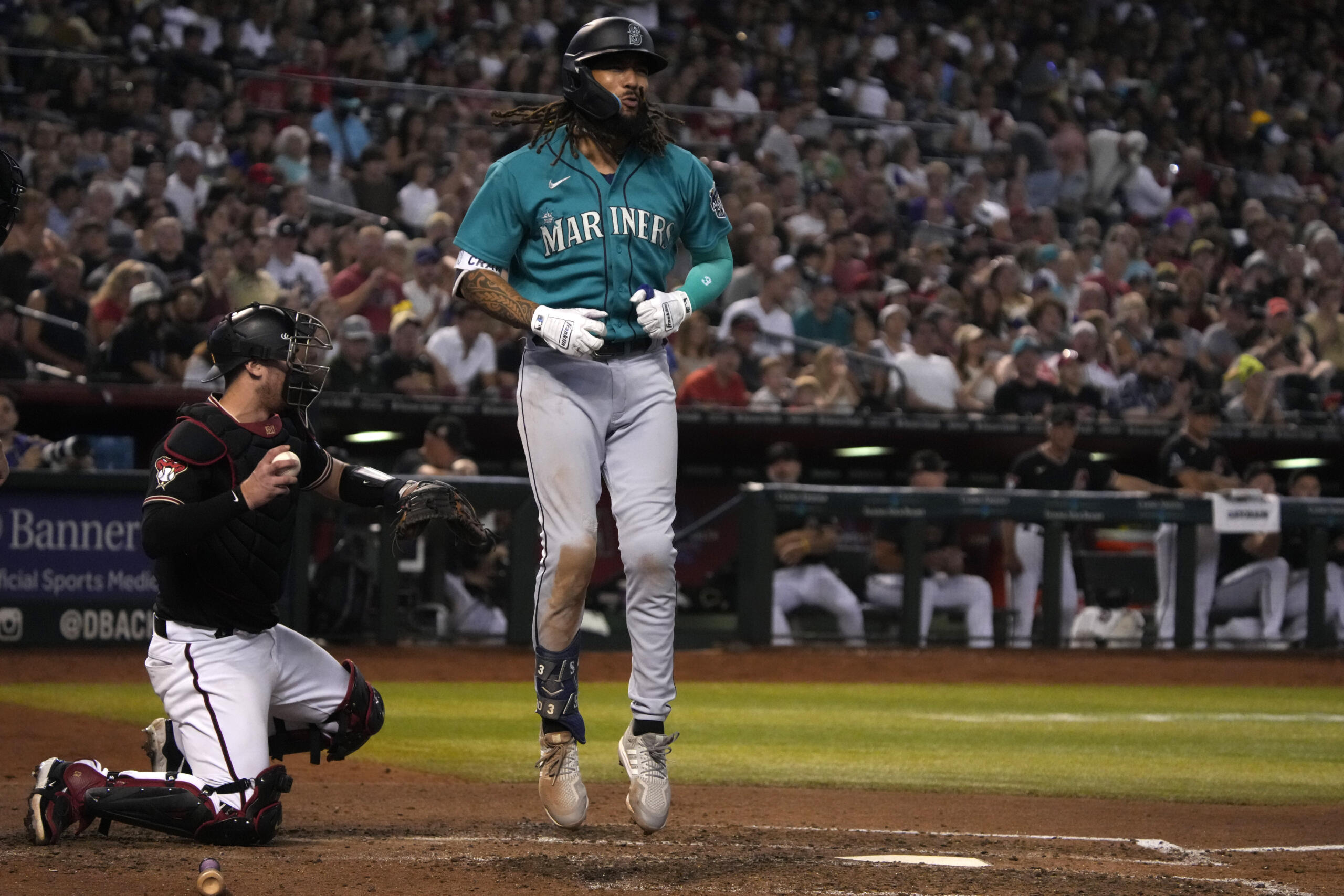 Seattle Mariners' J.P. Crawford, right, reacts after striking out against the Arizona Diamondbacks in the seventh inning during a baseball game, Saturday, July 29, 2023, in Phoenix.