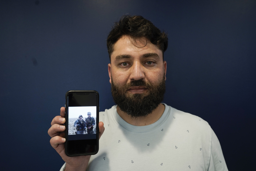 Mohammad Ahmadi poses for a portrait in Alexandria, Va., Friday, July 7, 2023, while holding a phone showing a digital photograph of his relative Nasrat Ahmad Yar who was shot and killed on July 3, in Washington, while working as a ride-share driver. Ahmad Yar was an Afghan immigrant who'd worked as an interpreter for the U.S. military in Afghanistan.