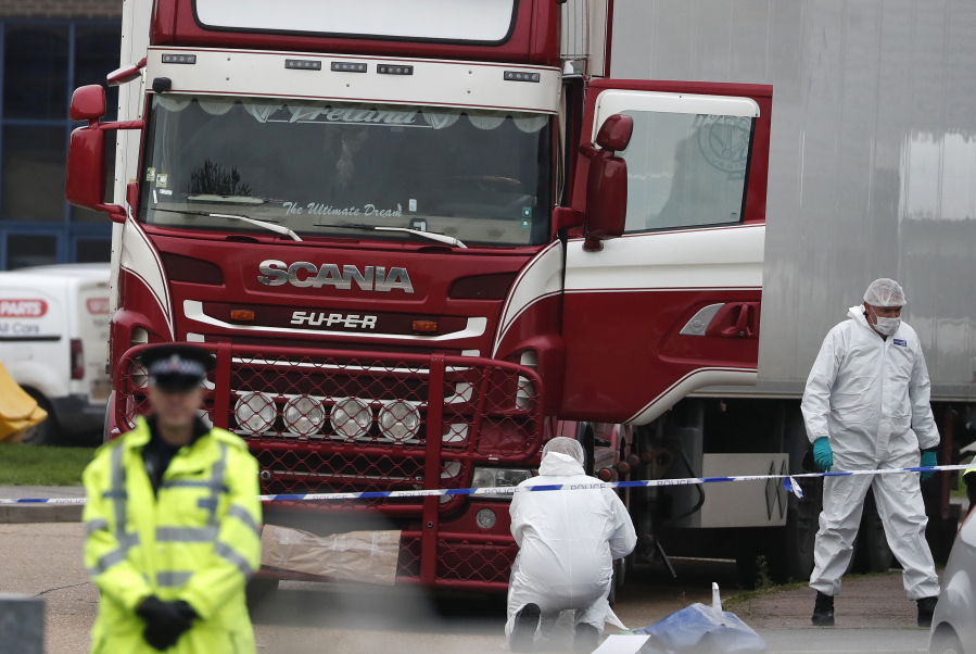 FILE - Forensic police officers attend the scene after a truck was found to contain a large number of dead bodies, in Grays, England, Oct. 23, 2019. A Romanian man who was part of an international human smuggling ring was sentenced Tuesday July 11, 2023, to more than 12 years in prison for the deaths of 39 migrants from Vietnam who suffocated were found lifeless in a truck trailer in England in 2019. Marius Mihai Draghici, 50, pleaded guilty last month to 39 counts of manslaughter and conspiracy to assist unlawful immigration.
