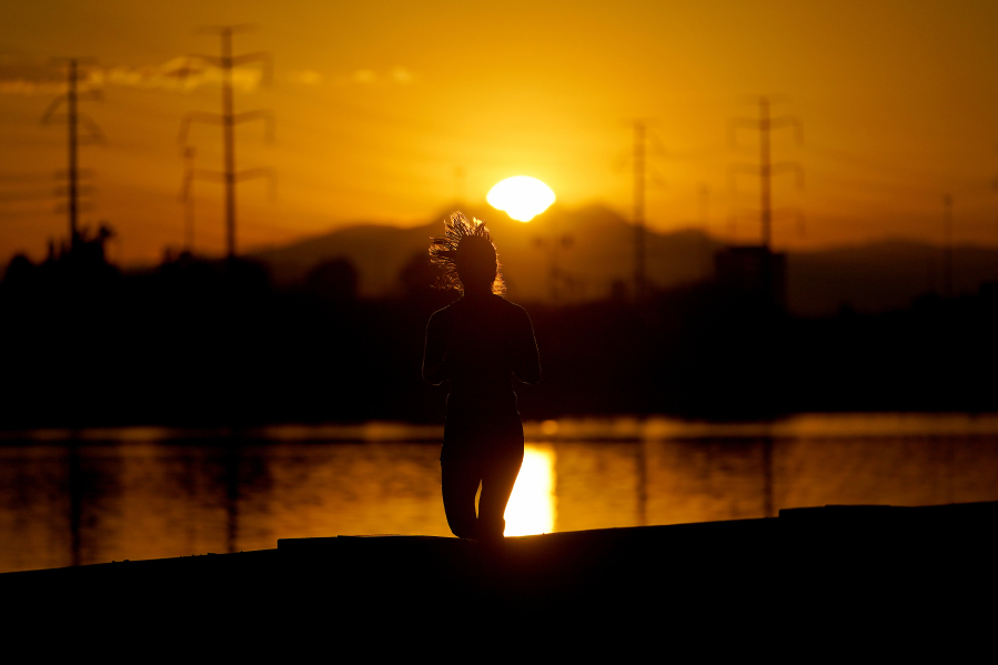 FILE - A runner jogs along Tempe Town Lake at sunrise,  July 12, 2023 in Tempe, Ariz. President Joe Biden plans to announce new steps to address the extreme heat that has threatened millions of Americans, most recently in the Southwest.