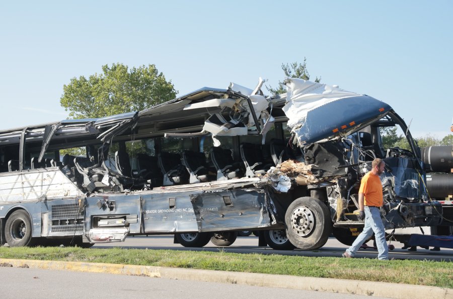 A worker helps clear the wreckage of a Greyhound bus that collided with tractor-trailers on the exit ramp to a rest area on westbound Interstate 70 in Highland, Ill., on Wednesday, July 12, 2023. (Christian Gooden/St.