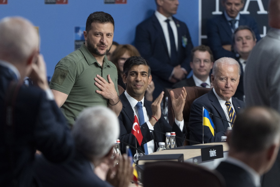 United States President Joe Biden and Britain's Prime Minister Rishi Sunak look on as Ukrainian President Volodymyr Zelenskyy stands while being recognized at the NATO Summit, Wednesday, July 12, 2023 in Vilnius, Lithuania.