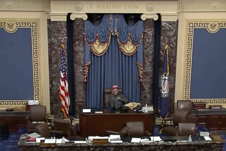 This image from U.S. Senate video, introduced at the trial of Bruno Joseph Cua, shows Cua sitting with his feet up in the Senate chamber on Jan. 6, 2021, during the riot at the U.S. Capitol.
