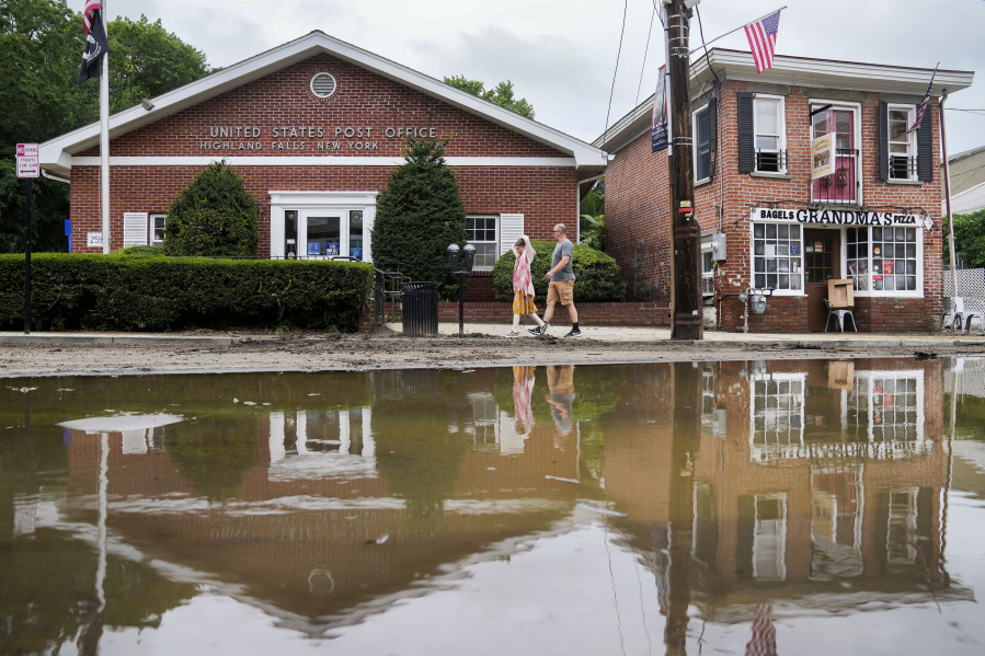 Pedestrians pass along Main Street that was damaged by flooding the previous day, Monday, July 10, 2023, in Highland Falls, N.Y. Scientists have long warned that more extreme rainfall is expected in a warming world.