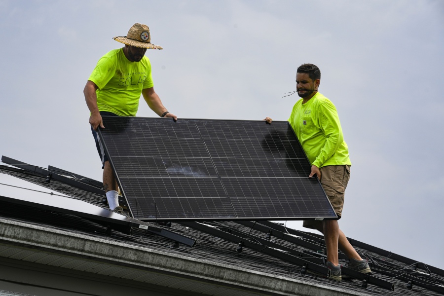 Even Berrios, left, and Nicholas Hartnett, owner of Pure Power Solar, install a solar panel on the roof of a home in Frankfort, Ky., Monday, July 17, 2023. Since passage of the Inflation Reduction Act, it has boosted the U.S. transition to renewable energy, accelerated green domestic manufacturing, and made it more affordable for consumers to make climate-friendly purchases, such as installing solar panels on their roofs.