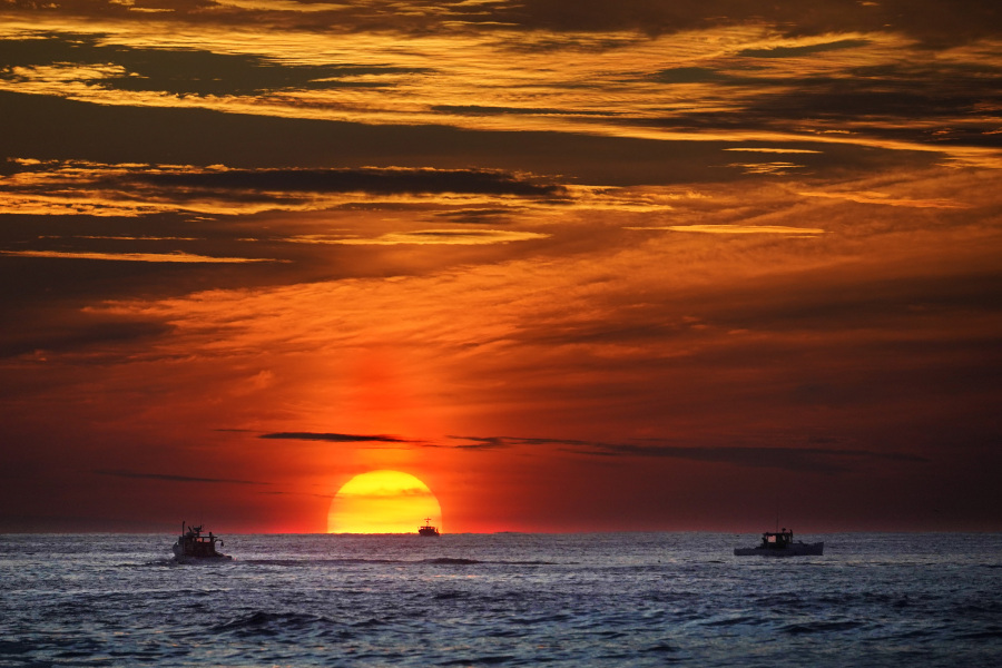 FILE - The sun rises over fishing boats in the Atlantic Ocean, Sept. 8, 2022, off of Kennebunkport, Maine. The United Nations body that regulates the world's ocean floor is preparing to resume negotiations in July 2023, that could open the international seabed for mining, including for materials vital for the green energy transition. (AP Photo/Robert F.