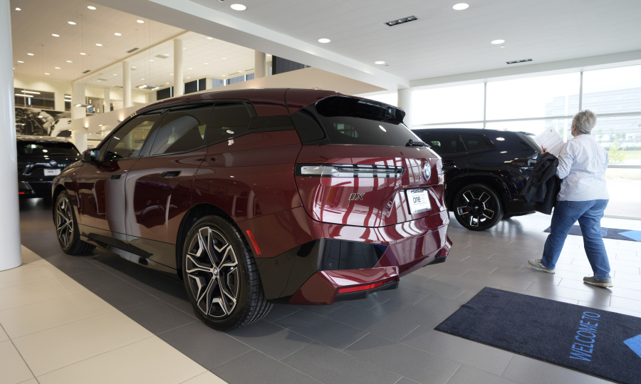 A shopper passes between a pair of unsold 2024 IX electric sports utility vehicles at a BMW dealership Wednesday, July 5, 2023, in Highlands Ranch, Colo. On Friday, The Commerce Department issues its June report on consumer spending.