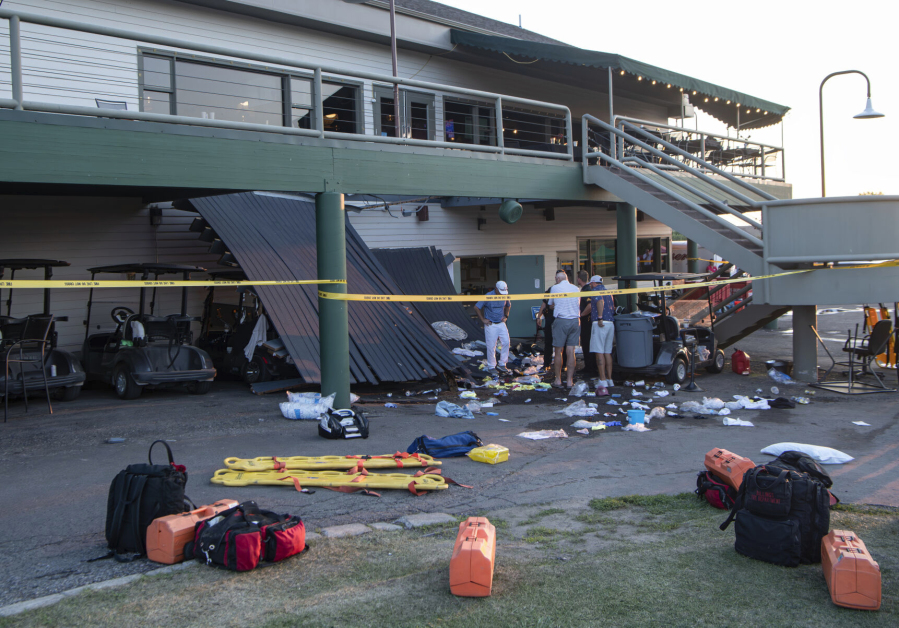 People talk behind police tape on the scene of a deck collapse at Briarwood Country Club in Billings, Mont., Sunday, July 23, 2023. The deck collapsed, leaving up to 25 people injured on Saturday evening, police and news reports said.