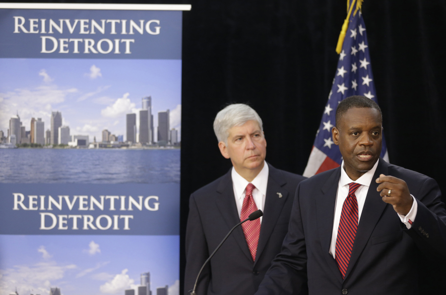 FILE - State-appointed emergency manager Kevyn Orr, right, and Michigan Gov. Rick Snyder address reporters during a news conference in Detroit, July 19, 2013, after Orr asked a federal judge for bankruptcy protection. Orr, the architect of Detroit's bankruptcy filing, admits it was a miserable process. But 10 years on he maintains the restructuring of the Motor City is among his most important accomplishments.