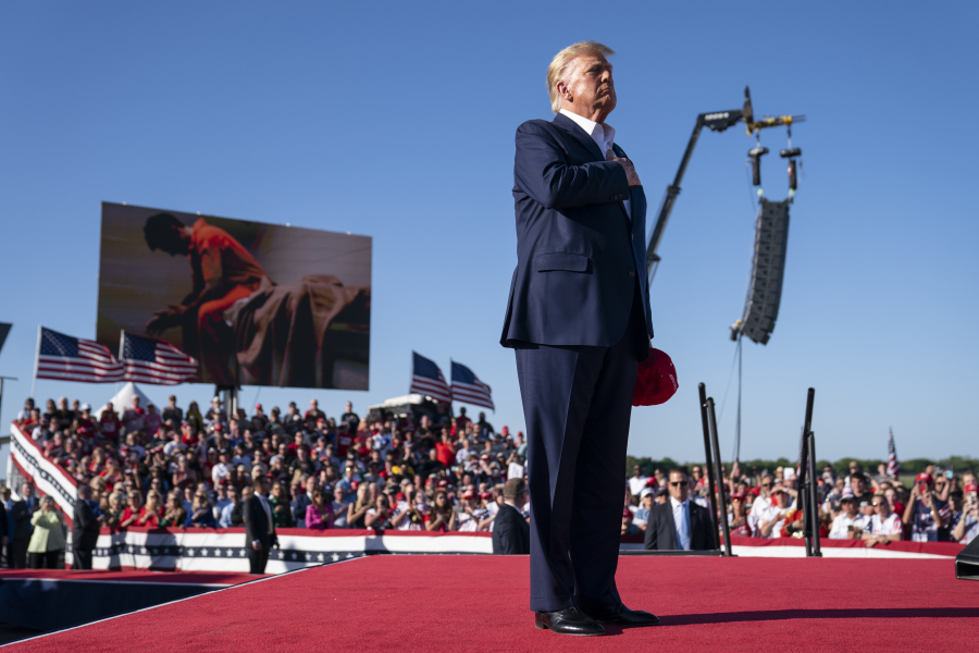 FILE - Former President Donald Trump stands while a song, "Justice for All," is played during a campaign rally at Waco Regional Airport, March 25, 2023, in Waco, Texas. The song features a choir of men imprisoned for their role in the Jan. 6, 2021, insurrection at the U.S. Capitol singing the national anthem and a recording of Trump reciting the Pledge of Allegiance.