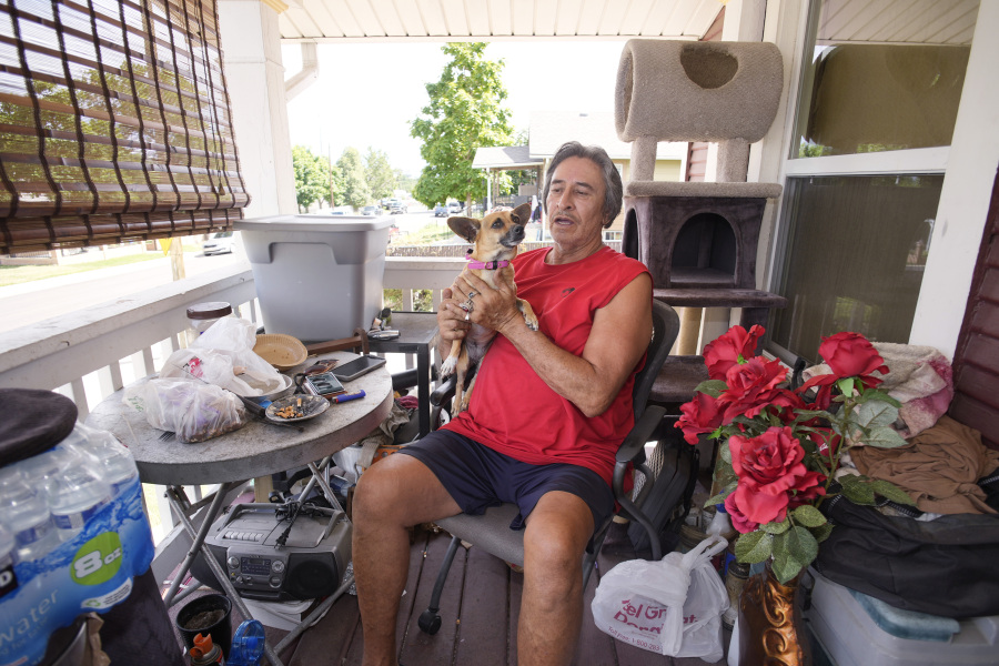 Ben Gallegos sits on the porch of his family's home in the Globeville neighborhood with his dog, Coca Smiles, as the daytime high temperature soars toward triple digits, Thursday, July 27, 2023, in north Denver. Gallegos has taken several measures to keep his home cool in spite of lacking central air conditioning.