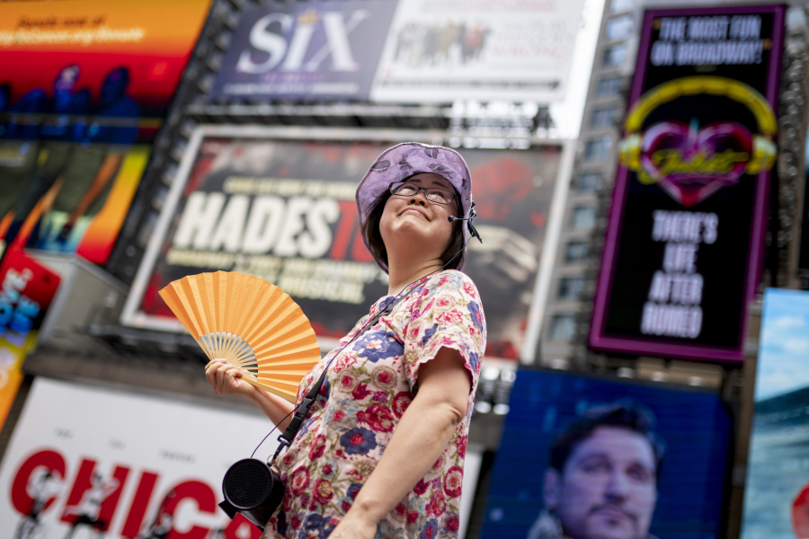 FILE - A tour guide fans herself while working in Times Square as temperatures rise, July 27, 2023, in New York. Nearly 60% of the U.S. population, are under a heat advisory or flood warning or watch as the high temperatures spread and new areas are told to expect severe storms.