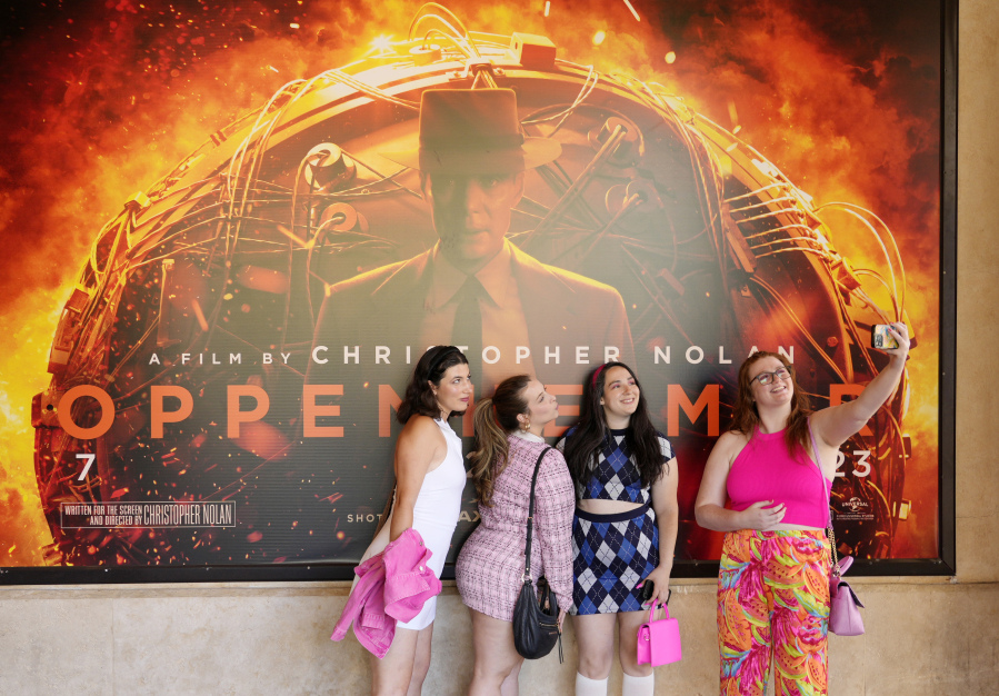 From left, Gabrielle Roitman, Kayla Seffing, Maddy Hiller and Casey Myer take a selfie in front of an "Oppenheimer" movie poster July 20 before they attended an advance screening of "Barbie," at AMC The Grove 14 theaters in Los Angeles.