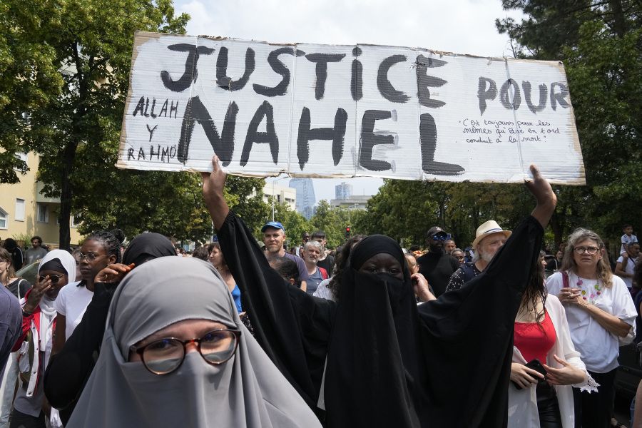 FILE - A woman shows a poster "Justice for Nahel" during a march for 17-year-old Nahel, Thursday, June 29, 2023 in Nanterre, outside Paris. Officially, race doesn't exist in France. But the killing of the French-born 17-year-old with North African roots has again exposed deep feelings about systemic racism that lie under the surface of the country's ideal of color-blind equality.