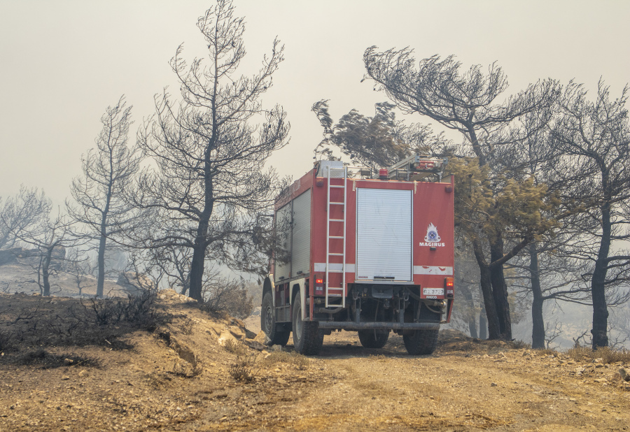 A fire-fighting vehicle makes its way through burnt trees during a forest fire, on the island of Rhodes, Greece, Sunday, July 23, 2023. Greek authorities say some 19,000 people have been evacuated from the Greek island of Rhodes as wildfires continue burning for a sixth day on three fronts.