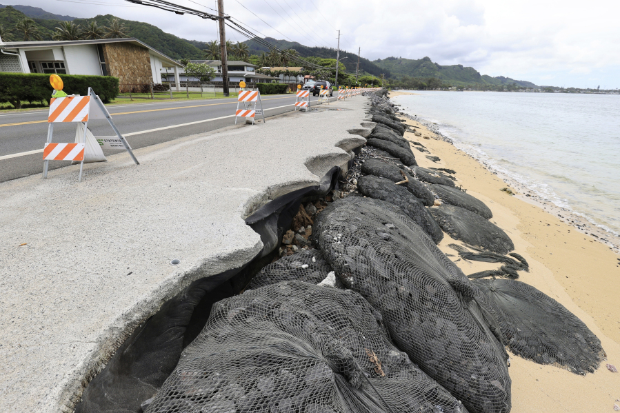 Cars drive down an eroded Kamehameha Highway, Thursday, May 11, 2023, in Hauula, Hawaii. Rising seas are eroding Hawaii's coast near homes with cesspools, pulling sewage out to sea.