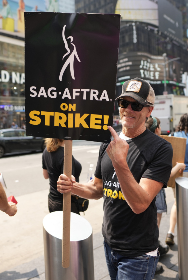 Actor Kevin Bacon carries a sign on a picket line outside Paramount in Times Square on Monday, July 17, 2023, in New York. The actors strike comes more than two months after screenwriters began striking in their bid to get better pay and working conditions and have clear guidelines around the use of AI in film and television productions.
