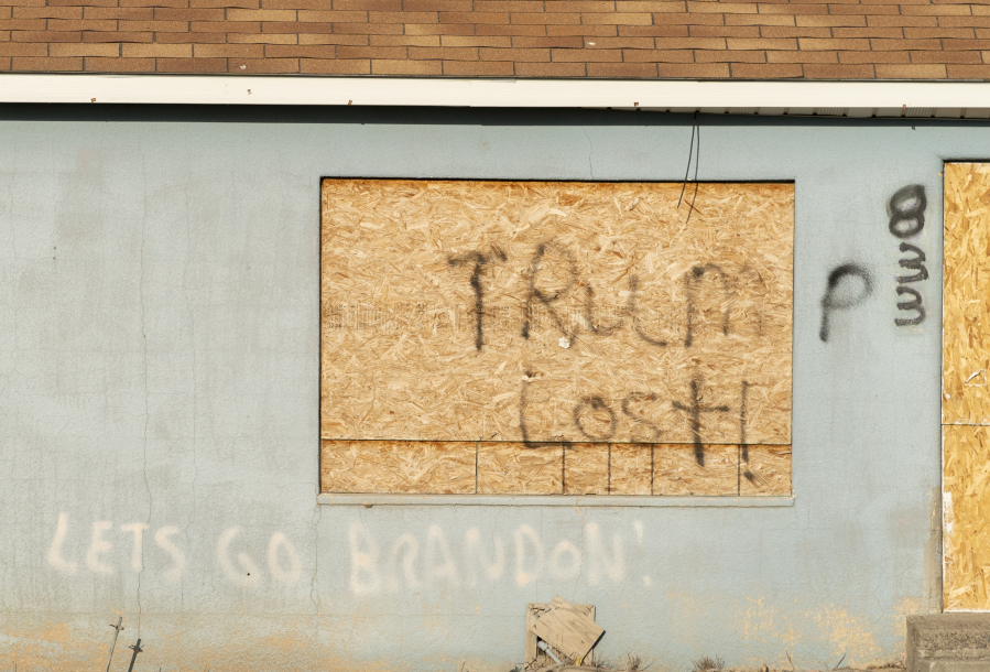 Opposing political graffiti reads, "Trump lost" and "Let's go Brandon," on the side of a boarded-up house, Saturday, July 8, 2023, near the county fairgrounds in Filer, Idaho.