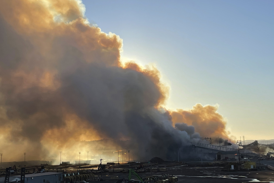 A large smoke plume from an industrial fire fueled by wood chip piles at an paper plant in Longview, Wash., is seen at sunset Tuesday, July 18, 2023. The fire at Nippon Dynawave Packaging is worsening air quality in northwest Oregon and southwest Washington and officials warned those in the immediate area to stay inside and keep doors and windows closed. No injuries have been reported and officials are investigating.