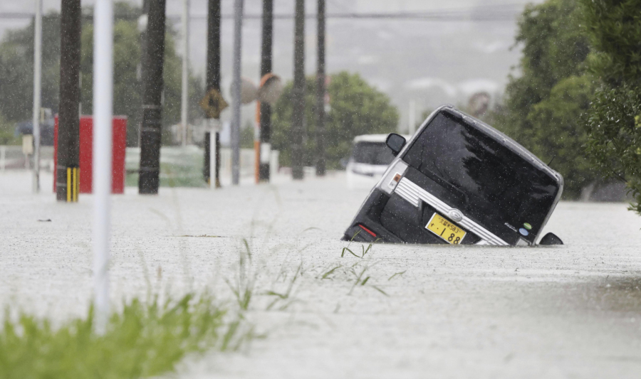 A vehicle is stuck on a street flooded due to a heavy rain in Kurume, Fukuoka prefecture, southern Japan Monday, July 10, 2023. Torrential rain is pounding southwestern Japan, triggering floods and mudslides Monday as weather officials issued emergency heavy rain warning in parts of on the southern most main island of Kyushu.