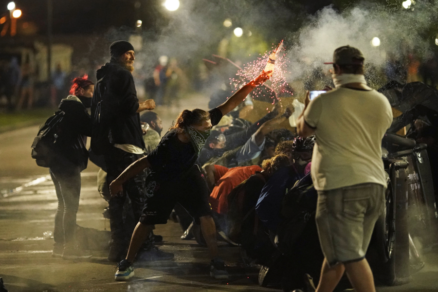 FILE - A protester tosses an object toward police during clashes outside the Kenosha County Courthouse, Aug. 25, 2020, in Kenosha, Wis., on a third night of unrest following the shooting of a Black man, Jacob Blake, whose attorney said he was paralyzed after being shot multiple times by police. On Tuesday, July 4, 2023, two freelance photographers filed a lawsuit alleging that police unlawfully shot them with rubber bullets during a protest over police racism in Wisconsin three years ago.