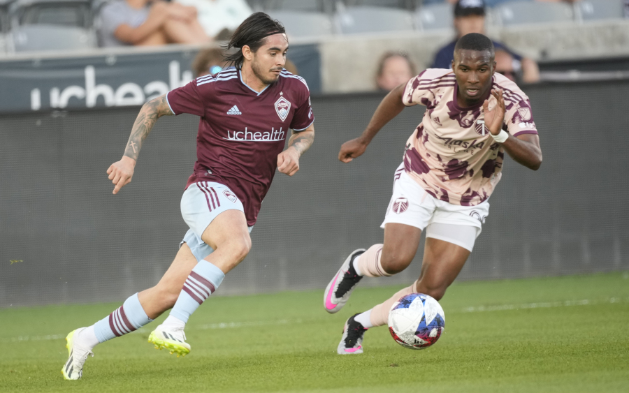 Colorado Rapids midfielder Braian Galvan, left, and Portland Timbers defender Juan David Mosquera pursue the ball in the second half of an MLS soccer match Wednesday, July 12, 2023, in Commerce City, Colo. The first half of the match was played Tuesday, July 4, before it was delayed by a rainstorm and rescheduled for Wednesday, July 12.