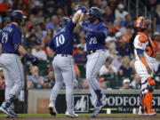 Seattle Mariners' Jarred Kelenic (10) and Eugenio Suarez (28) celebrate after they scored on a two-run home run by Suarez during the second inning of a baseball game Thursday, July 6, 2023, in Houston. Mariners' Cal Raleigh (29) and Houston Astros catcher Martin Maldonado, right, look on.