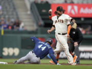 San Francisco Giants shortstop Brandon Crawford turns a double play as the Seattle Mariners' Julio Rodriguez (44) is forced out at second base in the first inning of a baseball game in San Francisco, Wednesday, July 5, 2023. The Mariners' Teoscar Hernandez was out at first base on the play.