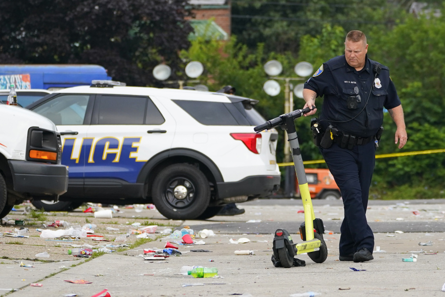 A police officer moves a scooter in the area of a mass shooting incident in the Southern District of Baltimore, Sunday, July 2, 2023. Police say a number of people were killed and dozens were wounded in a mass shooting that took place during a block party just after midnight.