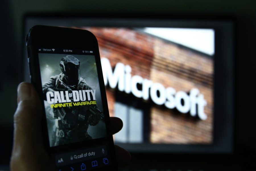 File - An image from Activision's Call of Duty is shown on a smartphone near a photograph of the Microsoft logo in this photo taken in New York, Thursday, June 15, 2023. A judge handed Microsoft a big victory on Tuesday, declining to stop its $69 billion takeover of video game maker Activision Blizzard.