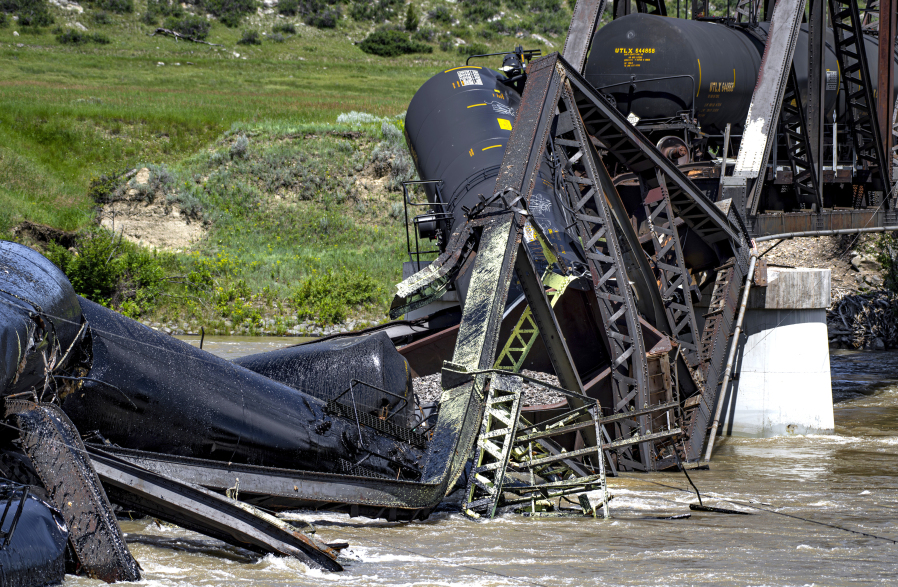 Rail cars remain in the river Sunday, June 25, 2023, after a railroad bridge collapsed on the Yellowstone River near Reed Point in Columbus, Mont. Crews on Sunday were testing the water and air quality along a stretch of the Yellowstone River where train cars carrying hazardous materials fell into the waterway following the bridge collapse.