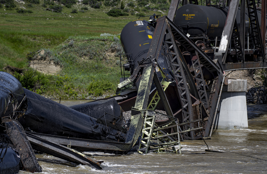 Rail cars remain in the river Sunday, June 25, 2023, after a railroad bridge collapsed on the Yellowstone River near Reed Point in Columbus, Mont. Crews on Sunday were testing the water and air quality along a stretch of the Yellowstone River where train cars carrying hazardous materials fell into the waterway following the bridge collapse.
