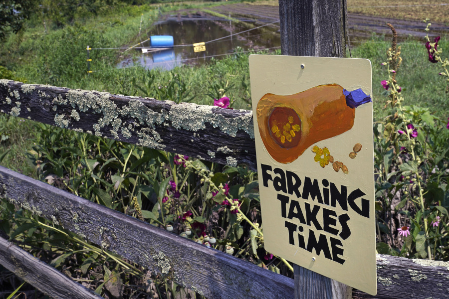 Flood waters remain on destroyed fields, at rear, as a sign informs visitors that "Farming Takes Time" at the Intervale Community Farm, following last week's flooding and this week's rains, Monday, July 17, 2023, in Burlington, Vt.