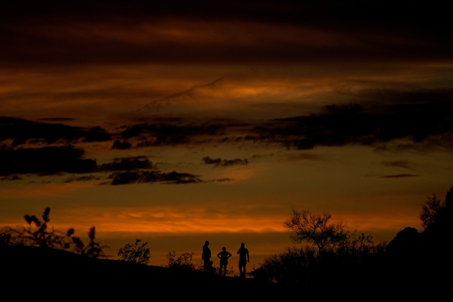 People stand atop a rock formation to watch the sunset, Sunday, July 30, 2023, in Phoenix. Phoenix hit its 31st consecutive day of at least 110 degrees Fahrenheit (43.3 Celsius). The National Weather Service said the temperature climbed to a high of 111 degrees Fahrenheit before the day was through.