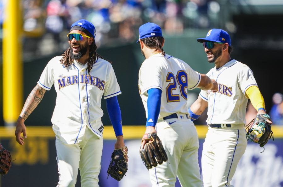 Seattle Mariners shortstop J.P. Crawford smiles with teammates third baseman Eugenio Suarez and second baseman Jose Caballero, right, as they celebrate their win over the Tampa Bay Rays after a baseball game, Sunday, July 2, 2023, in Seattle.