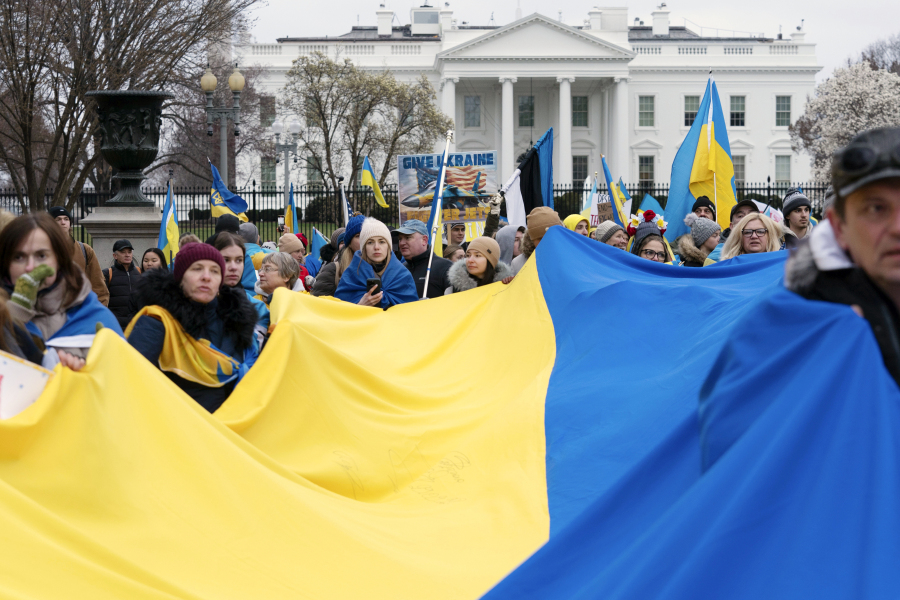 FILE - Demonstrators hold a Ukrainian flag as they march outside of the White House in support of Ukraine during a rally in Washington, Feb. 25, 2023. One of the architects of the covert U.S. strategy against the Soviets in Afghanistan has published a new memoir. In "By All Means Available," Michael Vickers calls on President Joe Biden's administration to increase its support for Ukraine's resistance against Russia.