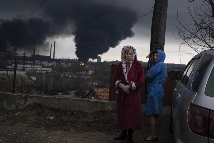 Women stand next to a car as smoke rises in the air in the background after shelling in Odesa, Ukraine, Sunday, April 3, 2022.