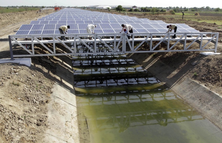 FILE - Indian workers give finishing touches to installed solar panels covering the Narmada canal at Chandrasan village, outside Ahmadabad, India, Sunday, April 22, 2012. The project brings water to hundreds of thousands of villages in the dry, arid regions of western India's Gujarat state.