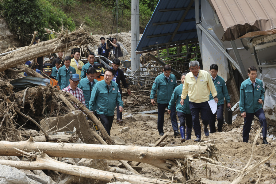 South Korean President Yoon Suk Yeol, third from left, looks around a flood damaged area in Yecheon, South Korea, Monday, July 17, 2023. Heavy downpours lashed South Korea a ninth day on Monday as rescue workers struggled to search for survivors in landslides, buckled homes and swamped vehicles in the most destructive storm to hit the country this year.